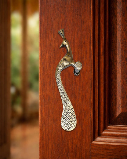 Decorative peacock-shaped brass handle on a wooden door