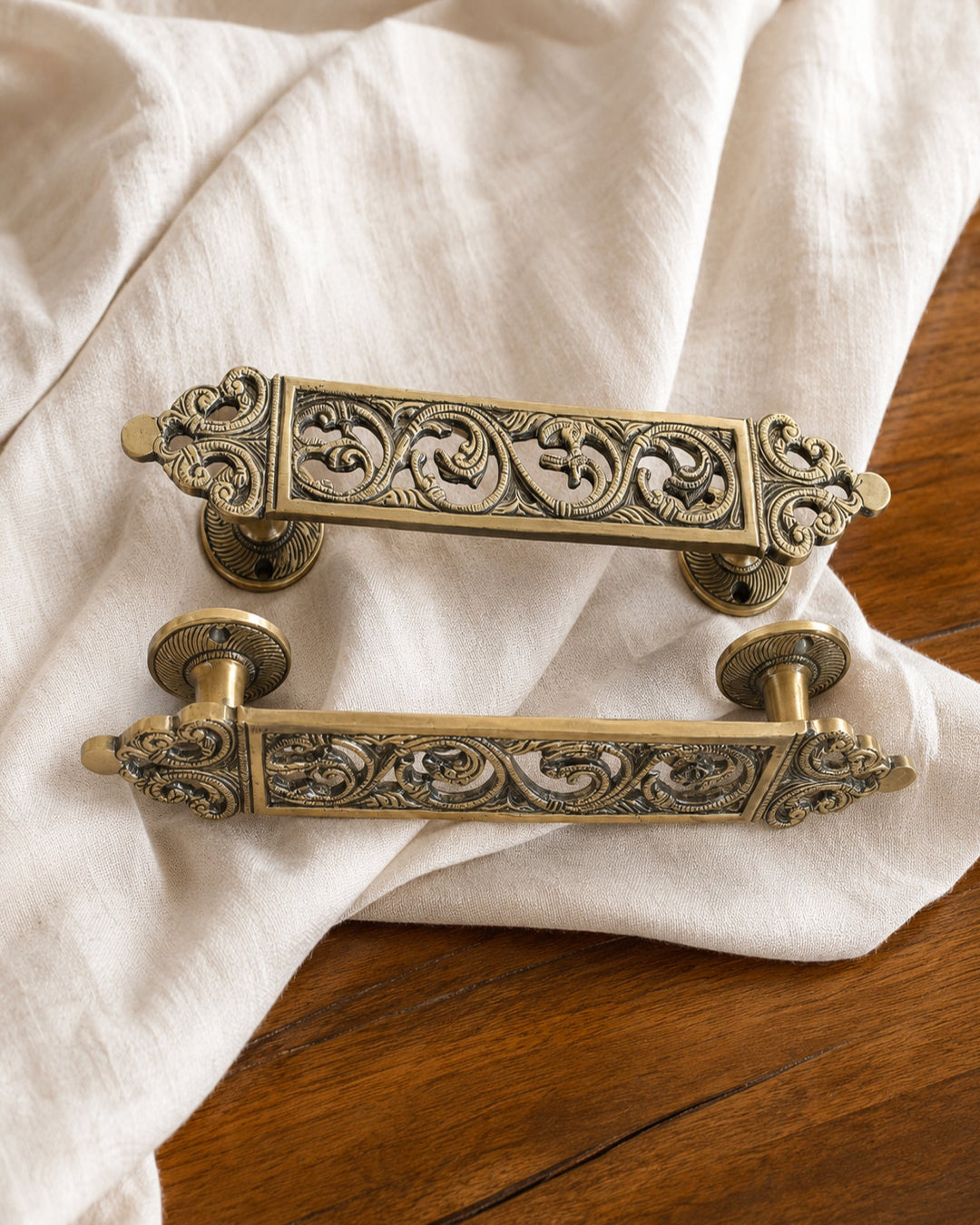 Decorative brass door handles on a white fabric background.