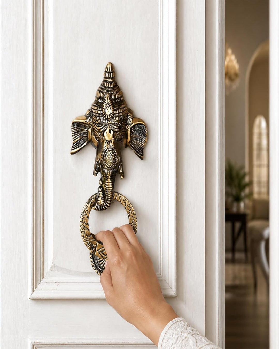 Decorative brass door knocker shaped like an elephant on a white door.