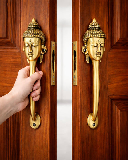 Gold door handle shaped like a Buddha head on a wooden door, with a hand opening it.