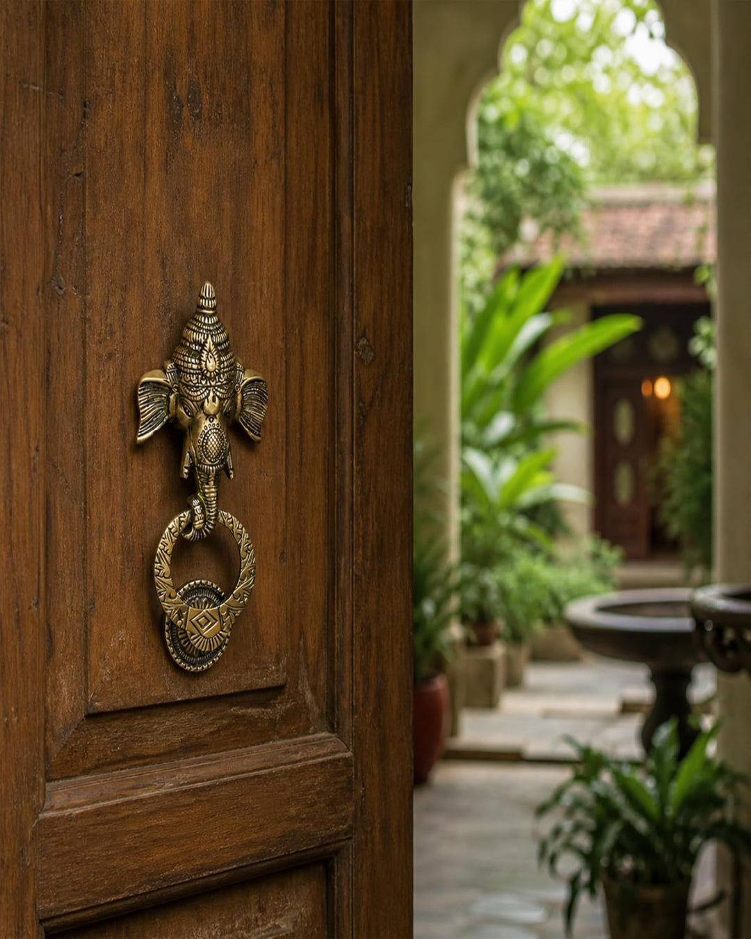 Decorative brass door knocker shaped like an elephant on a wooden door with a garden view.
