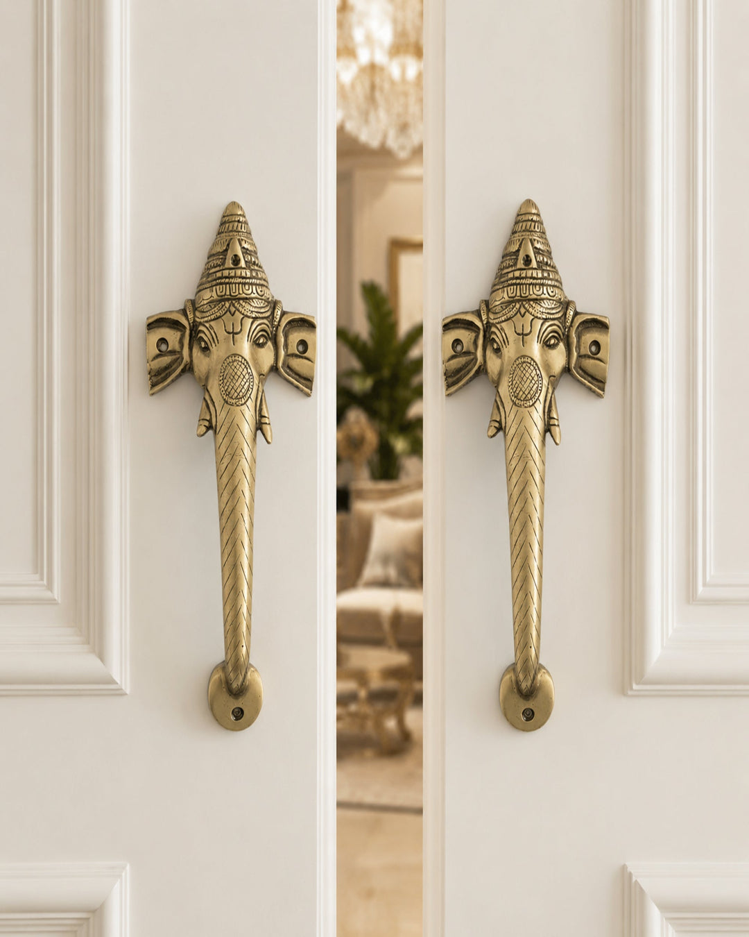 Decorative ganesha brass door handles on a white door.