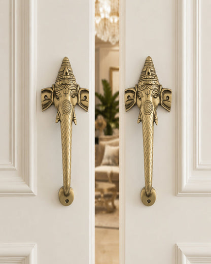 Decorative ganesha brass door handles on a white door.