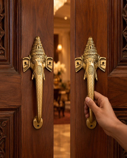 Decorative brass door handle shaped like an elephant on a wooden door, with a hand about to open it.
