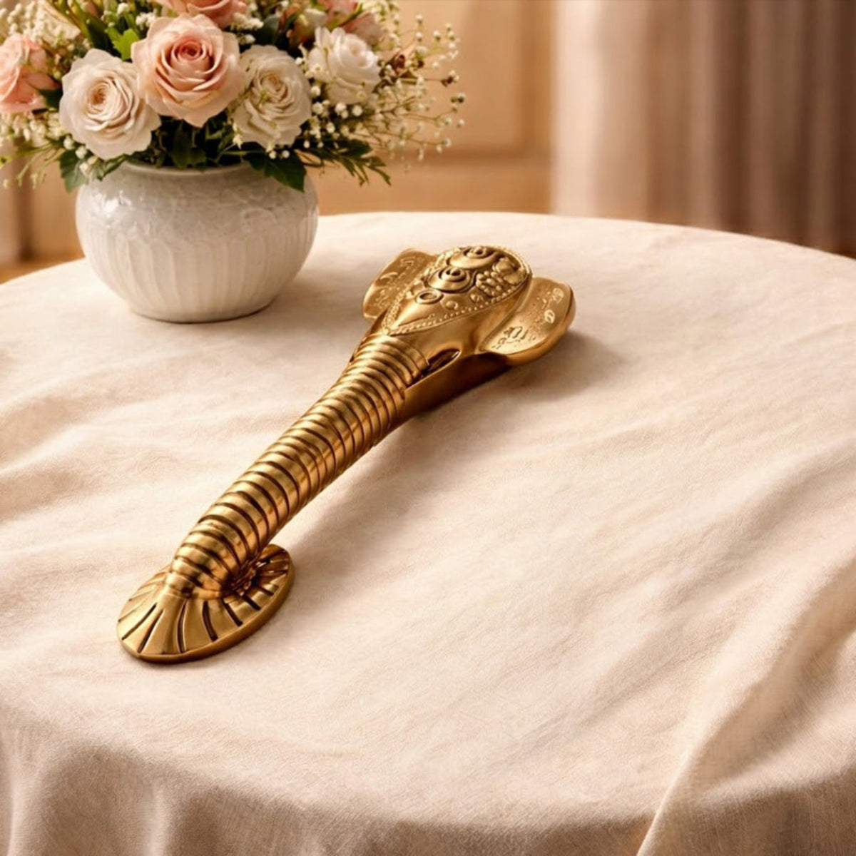 Decorative gold object on a table with flowers in the background