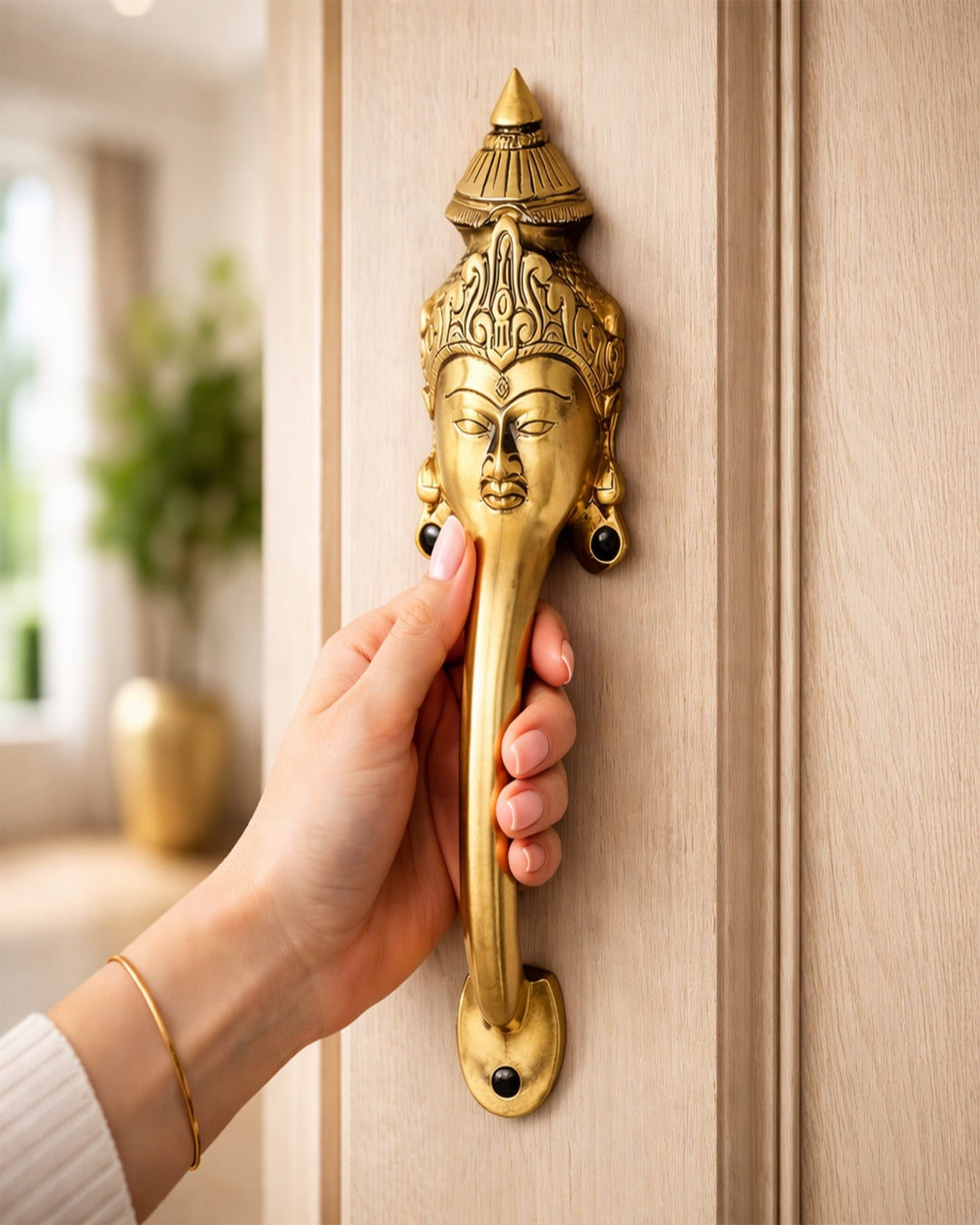 Hand opening a door with an Brass door handle featuring a face design.