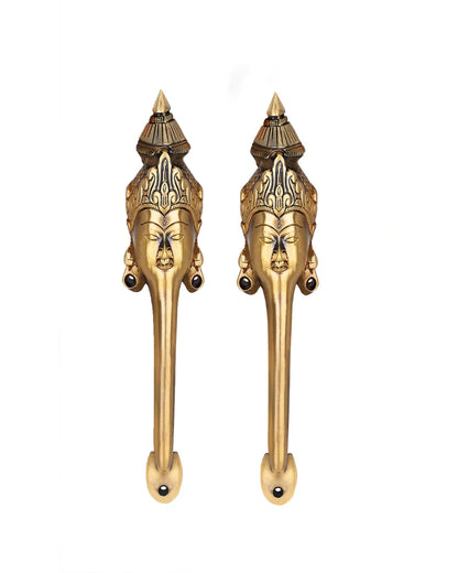 Pair of brass door handles with face designs on a white background.