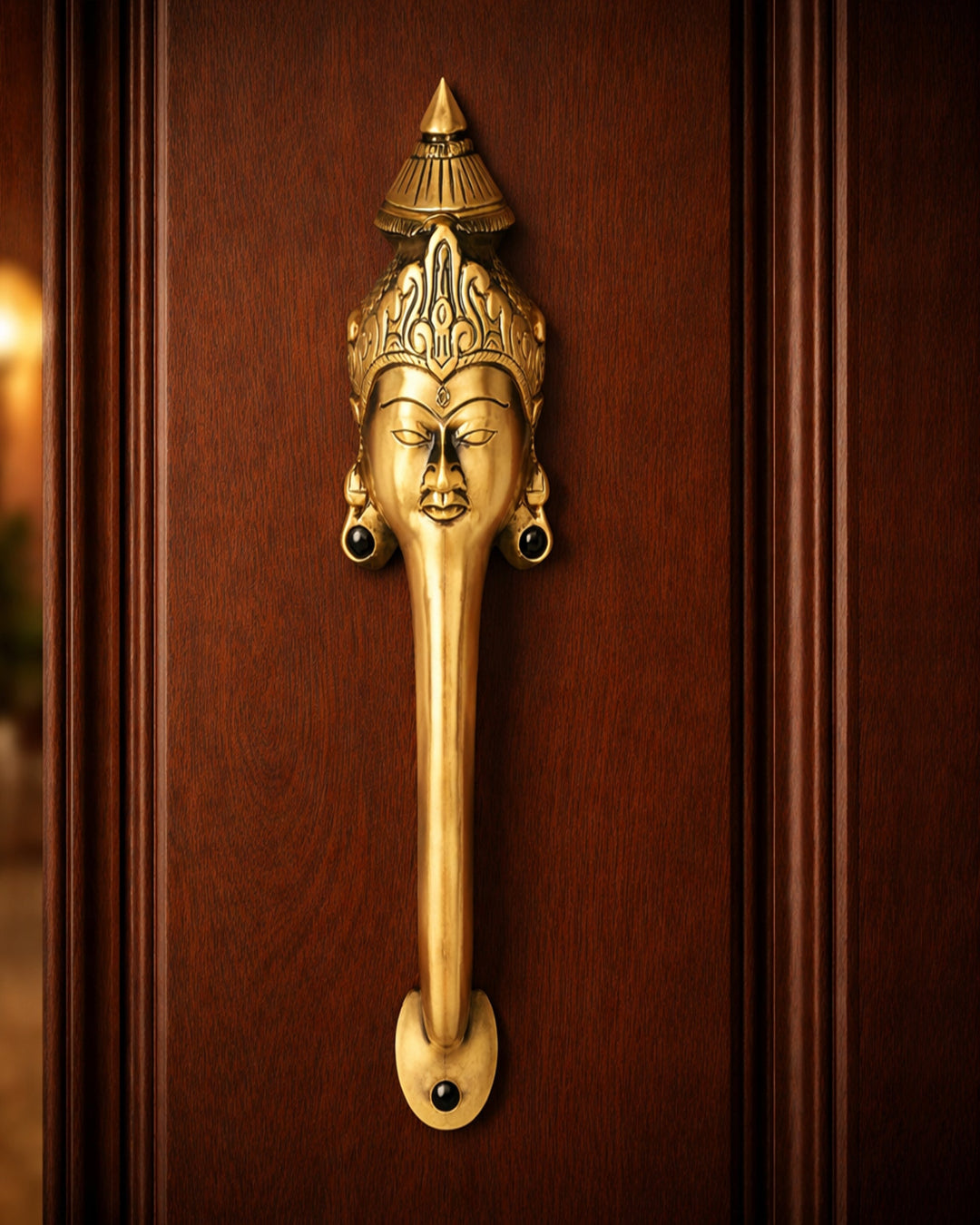 Decorative brass door handle with face design on a wooden door.