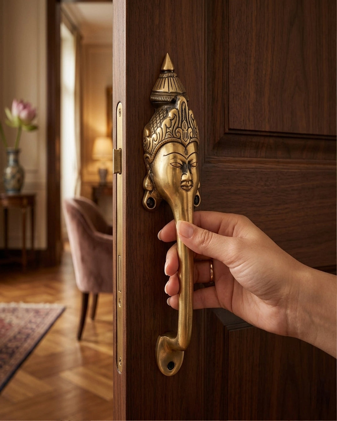 Hand opening a wooden door with an  gold handle featuring a face design, interior room visible.