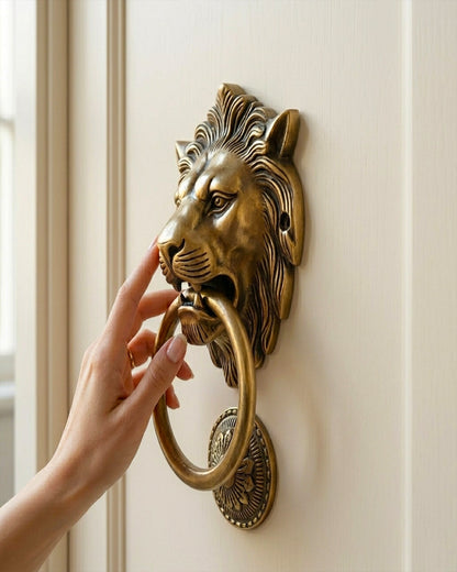 Hand using a lion-shaped brass door knocker on a white door