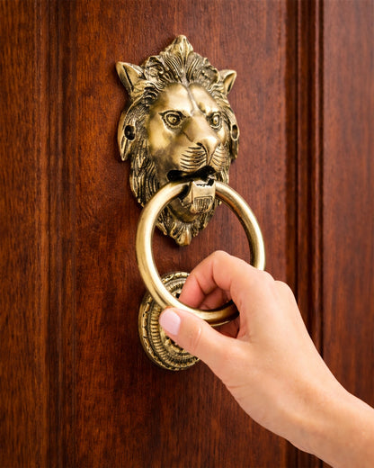 Hand using a lion-shaped brass doorknocker on a wooden door