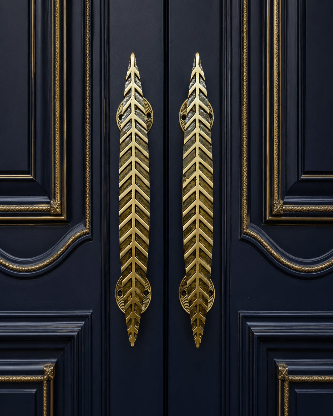 Two gold leaf-shaped door handles mounted on dark navy blue paneled doors with gold trim.