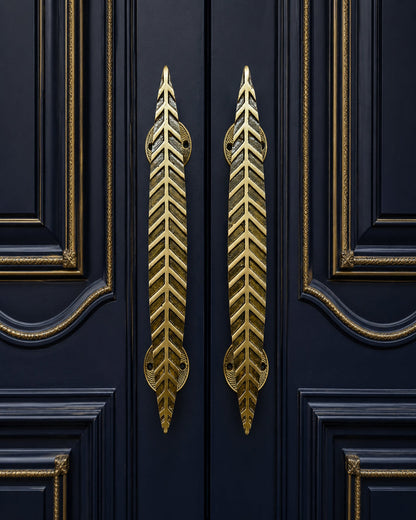 Two gold leaf-shaped door handles mounted on dark navy blue paneled doors with gold trim.