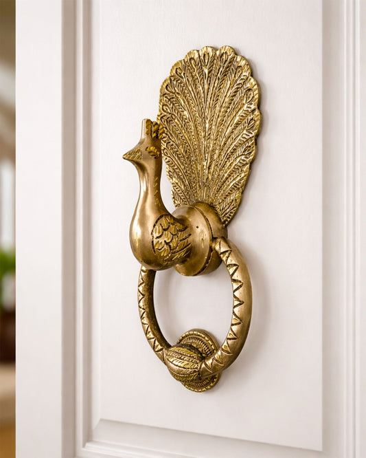 Decorative gold peacock door knocker on a white wooden door
