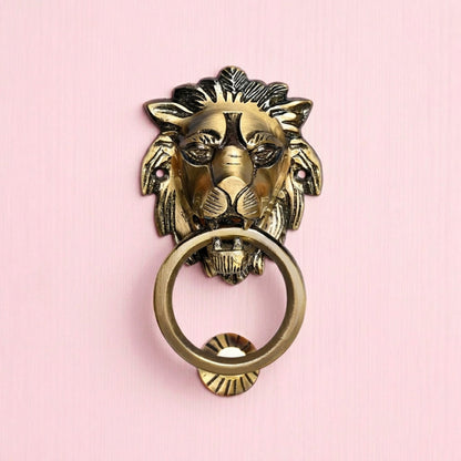 Brass lion head door knocker on a pink background