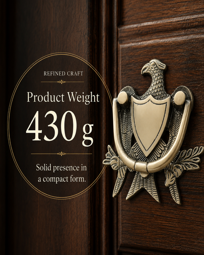 An antique-style eagle door knocker in a brushed brass/gold finish mounted on a dark brown wooden door. A circular text overlay on the left reads 'REFINED CRAFT Product Weight 430 g Solid presence in a compact form.