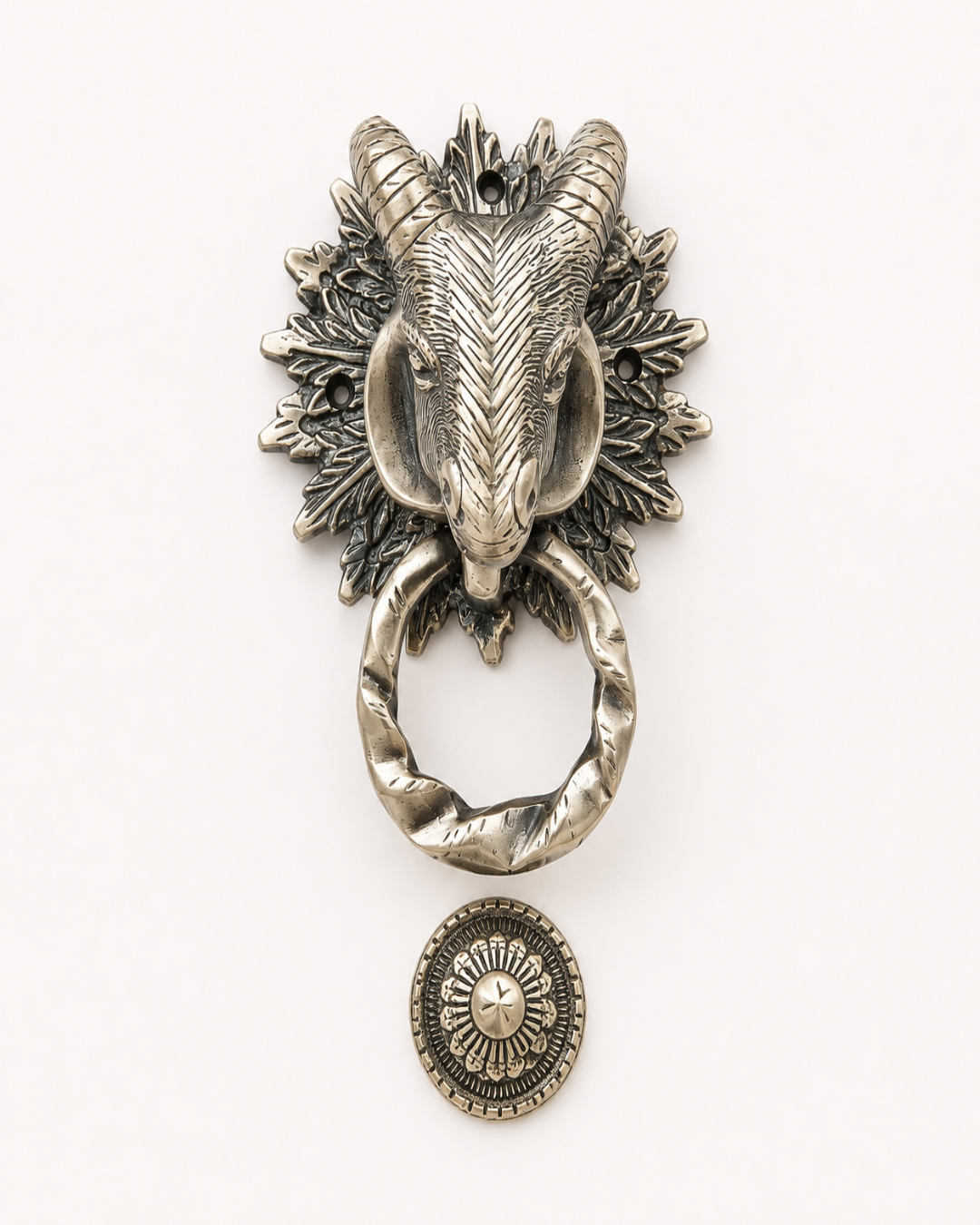 An antique-style silver ram head door knocker with a twisted ring and a matching round medallion, shown on a plain white background.