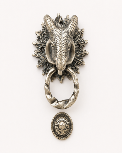 An antique-style silver ram head door knocker with a twisted ring and a matching round medallion, shown on a plain white background.