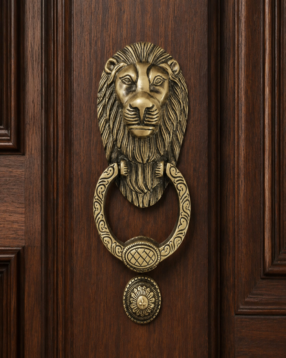 An ornate brass lion head door knocker with a matching ring and round doormat, mounted on a dark brown wooden door.