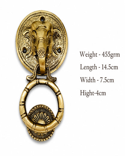 An antique brass door knocker featuring an elephant head on a circular backplate with a hanging ring, shown on a white background with text detailing its dimensions and weight.